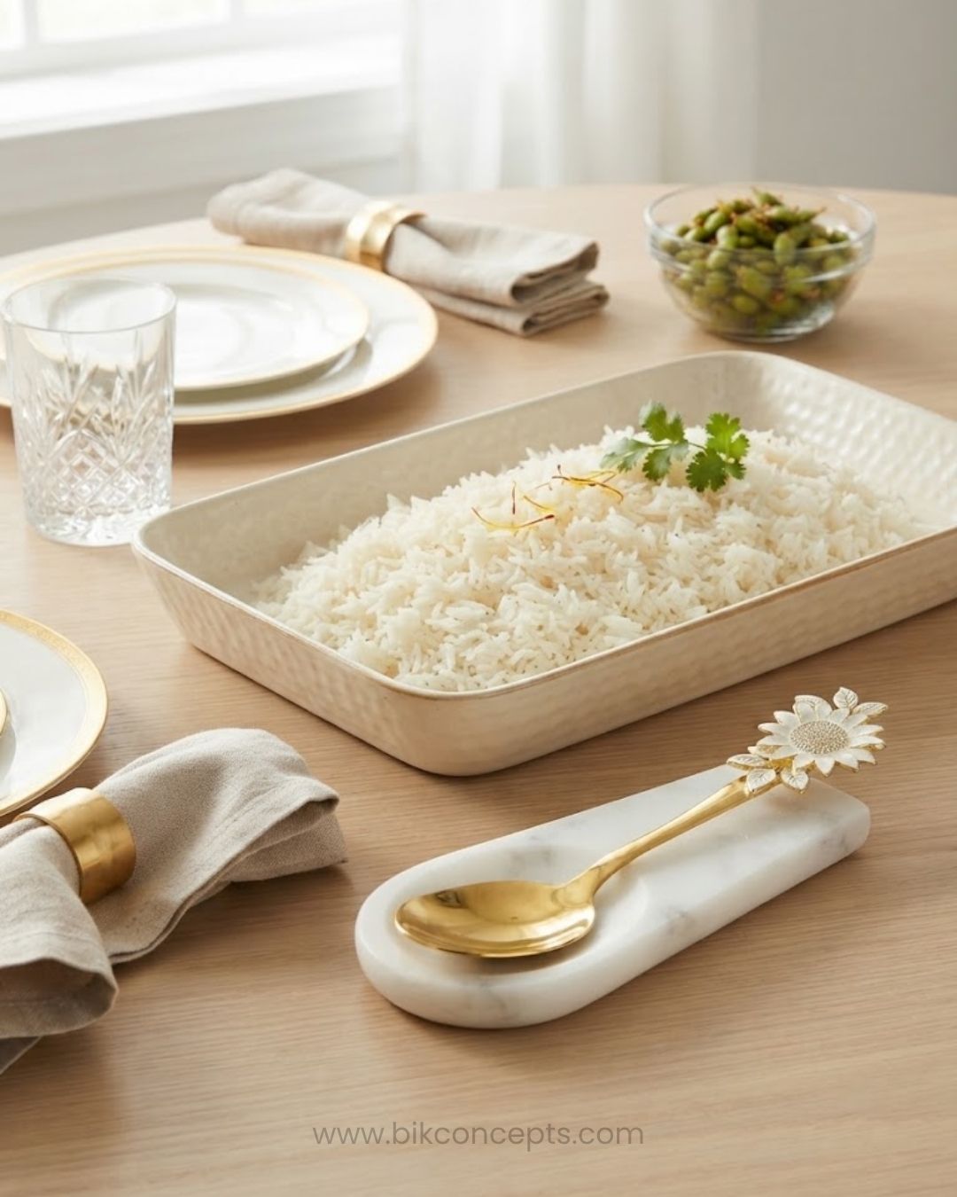 A beige rectangular ceramic baking dish filled with white rice, styled on a light wood table with gold-toned tableware, folded beige napkins, a glass, and a small bowl of green olives, Gold Stainless Steel Rice Serving Spoon, Sunflower Flat Rice Paddle, 11 Inch Flat Gold Serving Spoon, Set of 3 Gold Rice Spoons, Set of 5 Buffet Rice Paddles, Decorative Floral Handle Kitchen Utensils, Gold Biryani Serving Spoon Set, Luxury Tableware Rice Server, Decorative Flat Serving Utensils, High End Entertaining Rice Pa