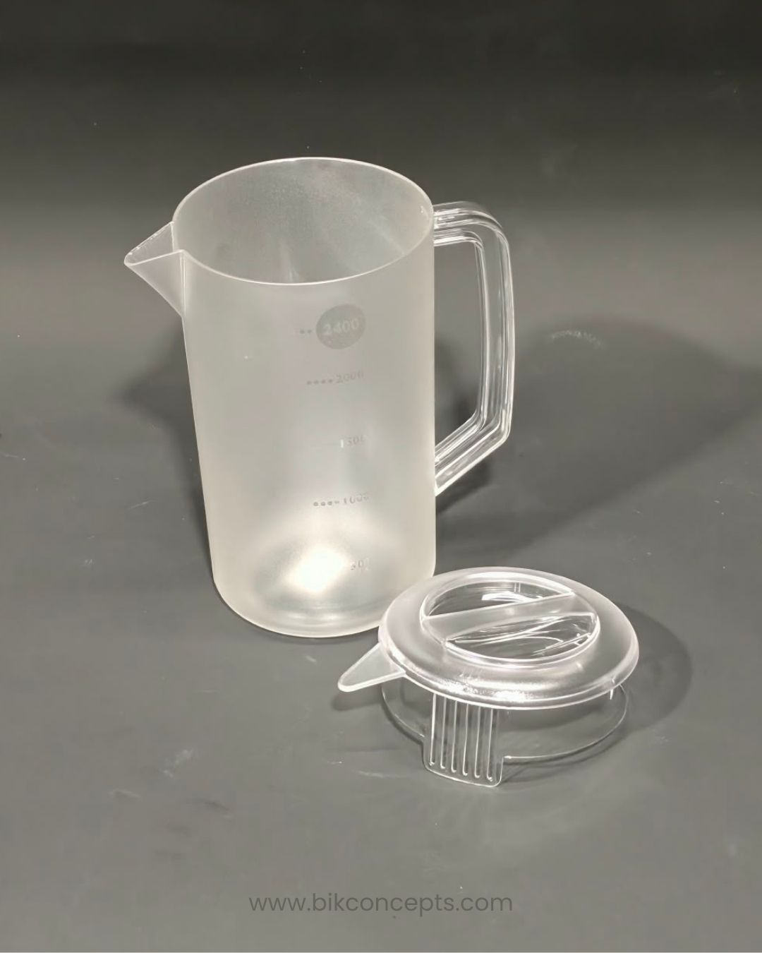 A translucent frosted plastic measuring pitcher with a handle and pouring spout, shown next to its clear plastic lid, Commercial Polypropylene Beverage Pitcher, 2.4 Liter Clear Plastic Water Jug, Shatterproof Catering Drink Pitcher, Hotel Buffet Beverage Service Pitcher, Measuring Plastic Pitcher with Lid, Restaurant Plastic Iced Tea Pitcher, Heavy Duty Commercial Plastic Jug, 2400ml Graduated Drink Pitcher, Outdoor Catering Plastic Pitcher, Clear Polypropylene Water Serving Jug