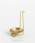 A minimalist brass-colored metal candle holder with a shallow bowl and a tall, slender upright stand, Gold Stainless Steel Spoon Rest, Vertical Ladle Holder Stand, Gold Utensil Rest for Buffets, Luxury Catering Tableware Accessories, Standing Spoon Holder with Drip Bowl, Brushed Gold Soup Ladle Stand, Catering Buffet Drip Tray, High End Dining Table Spoon Rest, Stainless Steel Tabletop Utensil Stand, Gold Buffet Counter Organizer