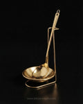 A polished gold-colored metal ladle with a matching shallow bowl and stand, Gold Stainless Steel Spoon Rest, Vertical Ladle Holder Stand, Gold Utensil Rest for Buffets, Luxury Catering Tableware Accessories, Standing Spoon Holder with Drip Bowl, Brushed Gold Soup Ladle Stand, Catering Buffet Drip Tray, High End Dining Table Spoon Rest, Stainless Steel Tabletop Utensil Stand, Gold Buffet Counter Organizer