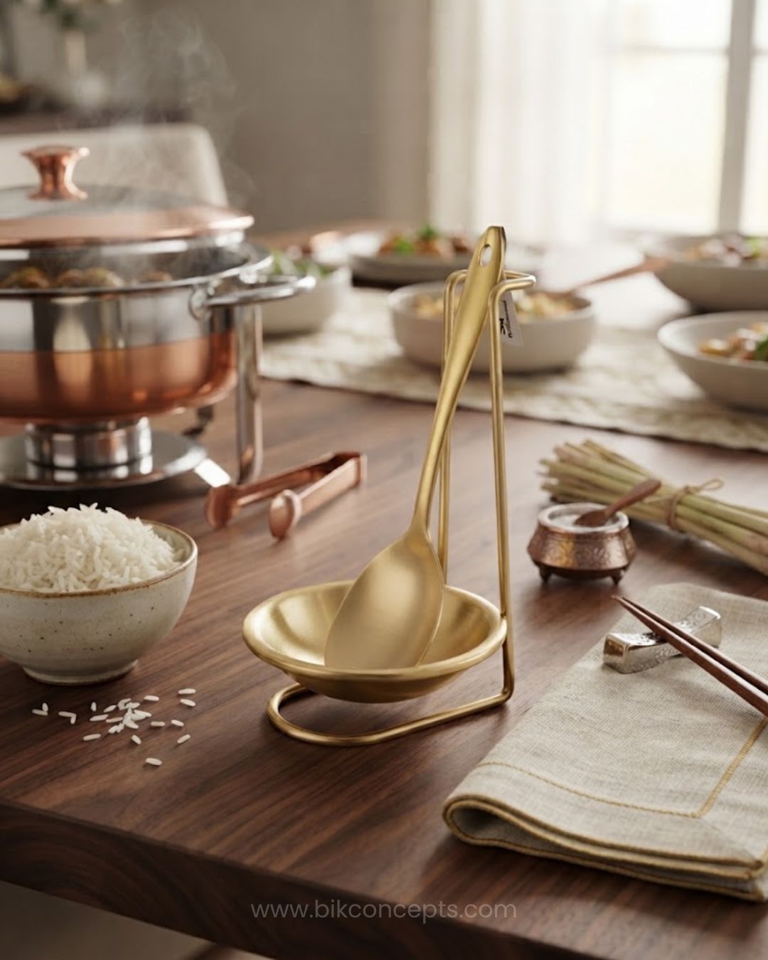 A brass-colored serving ladle set displayed on a wooden dining table, featuring a bowl and stand with a ladle,  Gold Stainless Steel Spoon Rest, Vertical Ladle Holder Stand, Gold Utensil Rest for Buffets, Luxury Catering Tableware Accessories, Standing Spoon Holder with Drip Bowl, Brushed Gold Soup Ladle Stand, Catering Buffet Drip Tray, High End Dining Table Spoon Rest, Stainless Steel Tabletop Utensil Stand, Gold Buffet Counter Organizer