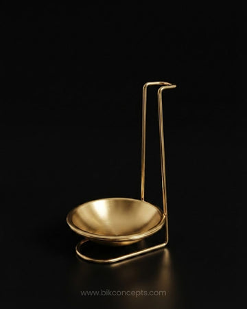 A polished gold metal oil lamp holder with a shallow bowl and a tall, curved support stand, Gold Stainless Steel Spoon Rest, Vertical Ladle Holder Stand, Gold Utensil Rest for Buffets, Luxury Catering Tableware Accessories, Standing Spoon Holder with Drip Bowl, Brushed Gold Soup Ladle Stand, Catering Buffet Drip Tray, High End Dining Table Spoon Rest, Stainless Steel Tabletop Utensil Stand, Gold Buffet Counter Organizer