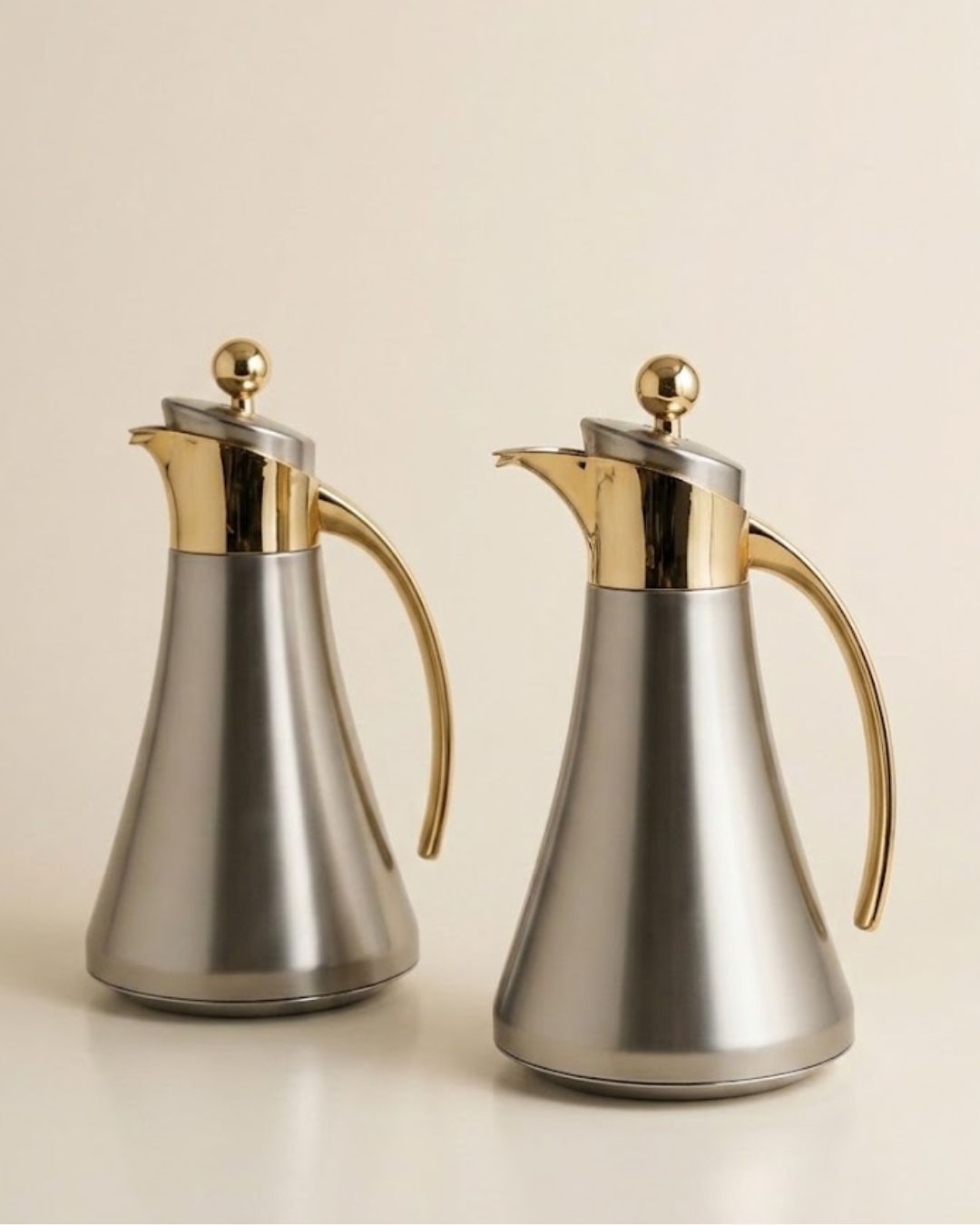 Two stainless steel carafes with polished gold-tone handles, spouts, and lid knobs,
Silver and Gold Coffee Thermos Set of 2, 1 Liter Stainless Thermal Coffee Carafe, Two Tone Metal Beverage Pitcher, Pink Glass Vacuum Flask Set, Luxury Catering Thermal Dispenser, Modern Gold Accent Tea Carafe, Insulated Hot Water Pitcher for Events, Luxury Silver Coffee Server Set, Stainless Steel Catering Thermos USA, Modern Metallic Beverage Carafe for Weddings