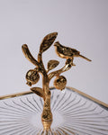 A gold-finished metal decorative sculpture of a bird perched on an ornate branch with leaves and textured fruit, mounted on a clear ribbed glass base against a light gray background.
Gold 2 Tier Glass Serving Stand, Square Tiered Dessert Stand, Luxury Home Party Serving Tray, Botanical Bird Food Stand, Cut Glass Square Appetizer Tray, Gold Metal and Glass Pastry Tower, Afternoon Tea Dessert Display, Decorative Square Fruit and Dessert Stand, Gold Pedestal Glass Serving Platter, Elegant Square Tiered Buffet 