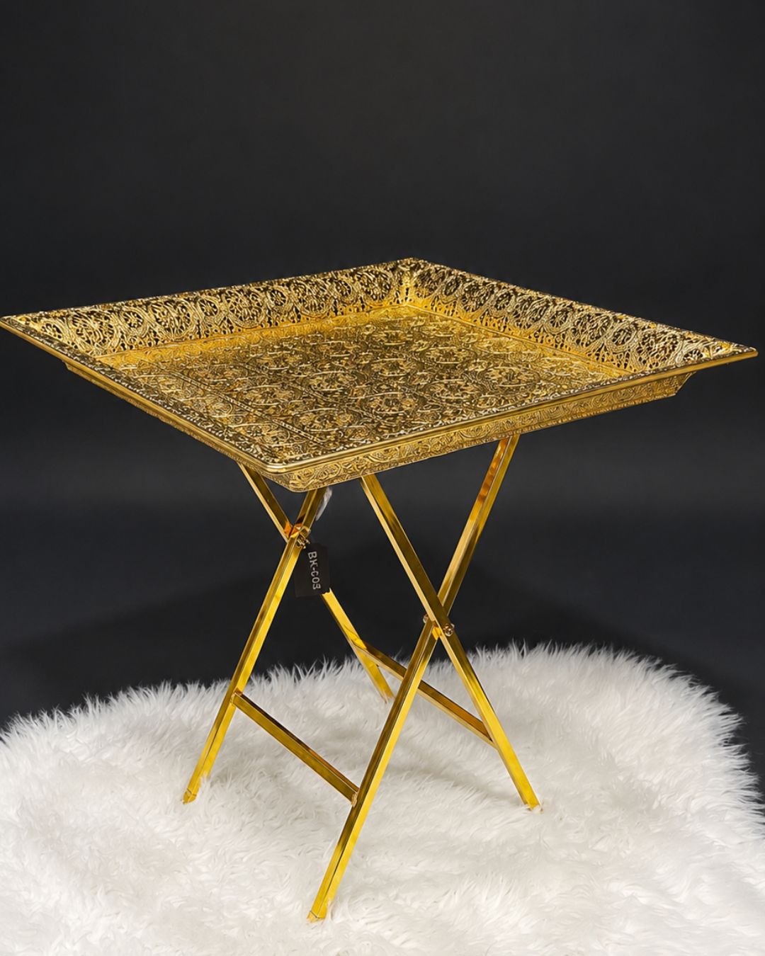 A square gold metal serving tray with an ornate embossed pattern, supported by a matching gold folding metal stand,Golden Square Serving Table, Embossed Metal Square Tray Table, Luxury Gold Accent Side Table, Moroccan Style Gold Tea Table, Designer Folding Drink Table USA, Filigree Metal End Table, Hollywood Regency Gold Furniture, Luxury Home Hosting Accessories, Decorative Square Metal Tray Table 21 Inch, High End Gold Bar Cart Alternative