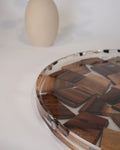 A close-up of a round epoxy tray filled with irregular wooden tiles in varying shades of brown, with a clear outer rim and a small black-and-white pattern along the edge, Wood and Epoxy Resin Serving Tray, Handcrafted Round Wood Tray, Mosaic Timber Resin Platter, Nature Enthusiast Home Decor, Clear Resin Charcuterie Board, Organic Wood Coffee Table Tray, Artisan Resin Serving Platter, Rustic Modern Wood Accent Tray, Clear Resin Drink Tray, Eco Friendly Natural Wood Serving Board