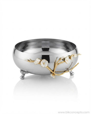 A polished silver-colored metal bowl with three small feet, decorated with a gold branch motif featuring white flower petals, 9 Inch Stainless Steel Footed Bowl, Luxury Jasmine Centerpiece Bowl, High End Floral Decor Bowl for Home, Botanical Metal Server for Catering, Silver Footed Serving Basin, Premium Catering Food Presentation USA, Designer Tabletop Centerpiece Vessel, Gold and Silver White Flower Bowl, Luxury Wedding Tableware, Decorative Metal Bowl for Console