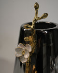 A close-up of a glossy black ceramic vase featuring an ornate gold branch with white enamel flowers and gold accents on the side, 12 Inch Stainless Steel Vase, Luxury Jasmine Flower Vase, High End Metallic Centerpiece Vase, Botanical Floral Decor Vase for Catering, Modern Silver Tabletop Vase, Premium Event Floral Presentation USA, Designer Metal Console Vessel, Gold and Silver White Flower Vase, Luxury Wedding Centerpiece Vase, Tarnish Resistant Stainless Steel Decor