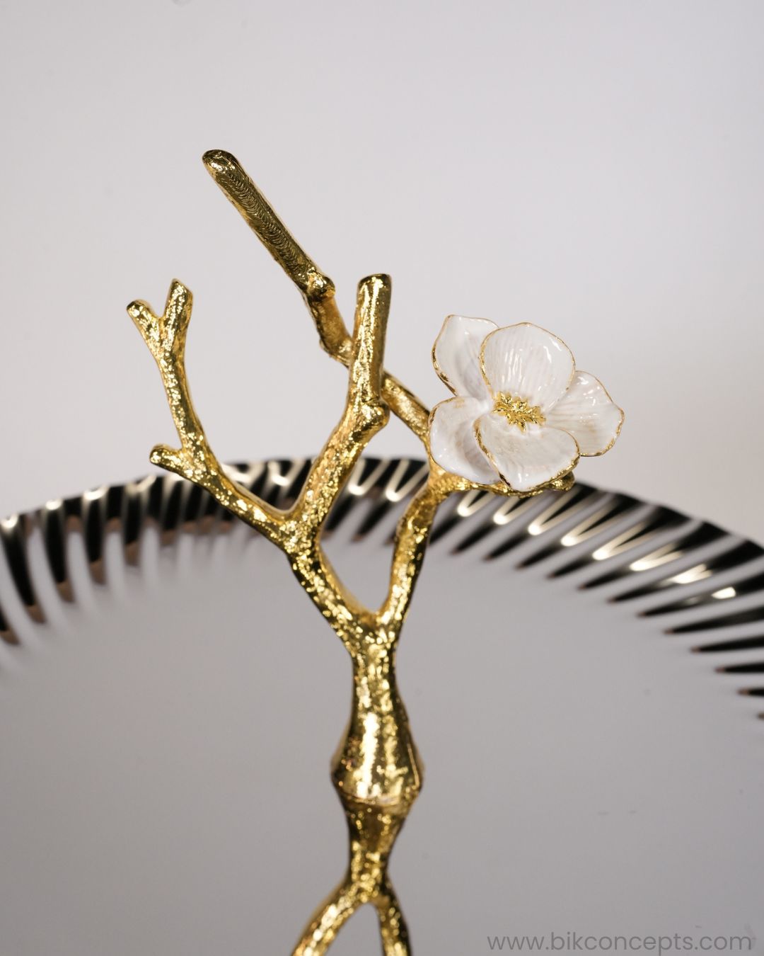 A close-up of a decorative gold branch sculpture with a white flower accent, 2 Tier Stainless Steel Platter, Luxury Tiered Dessert Stand, Jasmine Collection Serving Tray, High End Catering Platter USA, Silver Tiered Pastry Stand, Botanical Metal Buffet Display, Gold and Silver Tiered Tray, Designer Afternoon Tea Stand, Luxury Wedding Food Display, Decorative 2 Tier Metal Server
