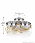 Three small metallic bowls arranged on a decorative gold branch-style base with white flower accents, shown on a white background with overlaid dimension labels reading bowl diameter 4in and total height 2in.