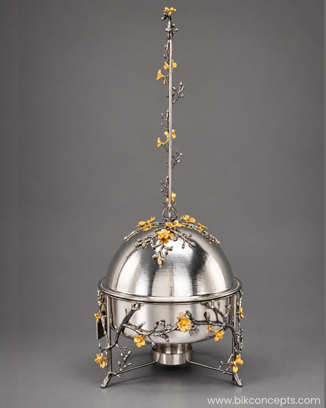 A silver-toned metal chafing dish with a domed lid and three legs, decorated with silver branches and small golden floral accents, 6L stainless steel chafing dish, luxury chafing dish, black and gold chafing dish, floral buffet server, gold chafing dish stand, elegant buffet warmer, catering chafing dish, restaurant buffet server, party food warmer, BIK Concepts