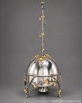 A silver-toned metal chafing dish with a domed lid and three legs, decorated with silver branches and small golden floral accents, 6L stainless steel chafing dish, luxury chafing dish, black and gold chafing dish, floral buffet server, gold chafing dish stand, elegant buffet warmer, catering chafing dish, restaurant buffet server, party food warmer, BIK Concepts