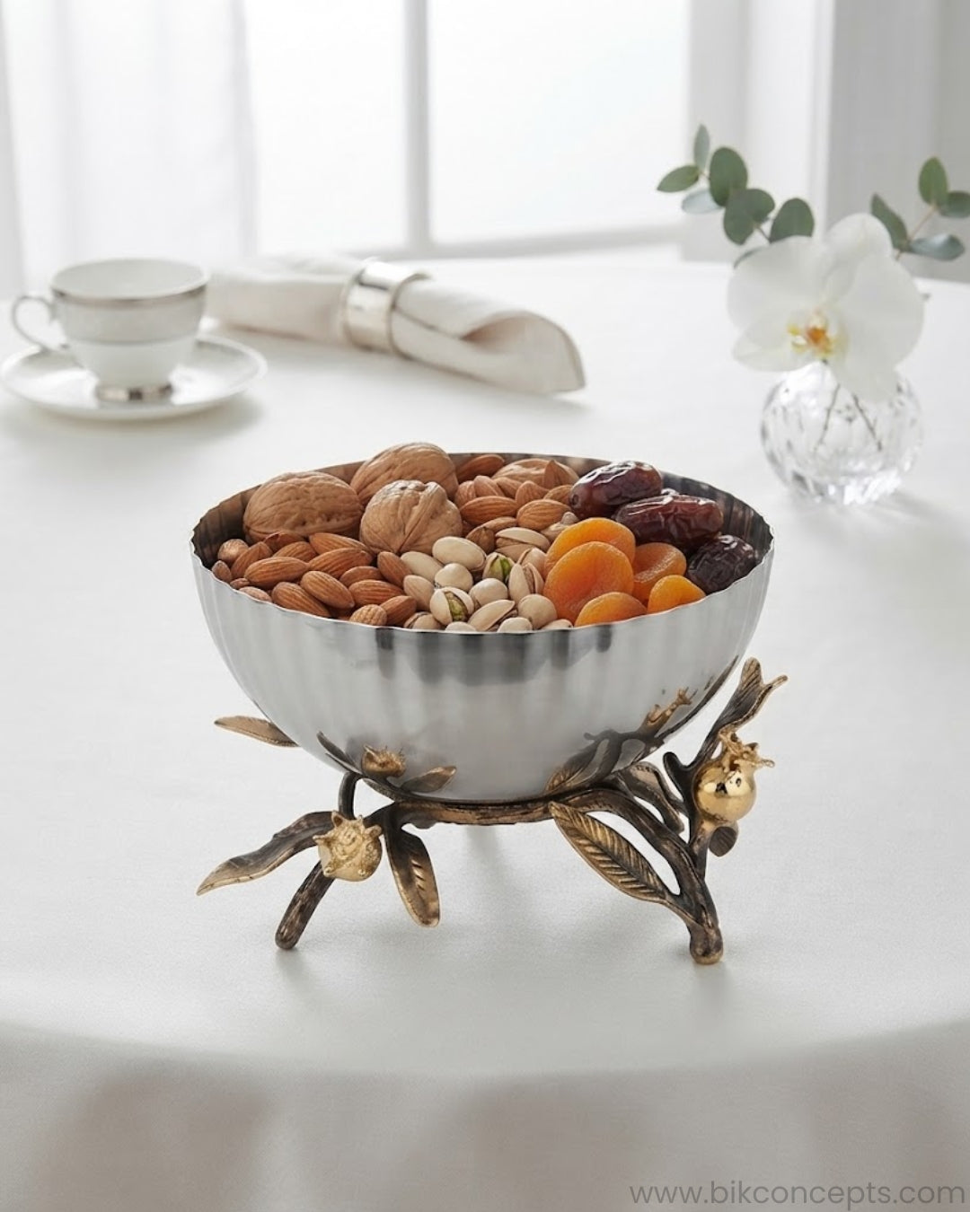 A decorative metal bowl with a polished silver-toned interior and a sculptural branch-and-fruit base in antique gold and dark bronze tones, shown on a clean white background with a faint reflection below, 7.8 Inch Stainless Steel Serving Bowl, Luxury Pomegranate Centerpiece Bowl, High End Pedestal Salad Bowl, Botanical Metal Bowl for Catering, Fluted Silver Serving Dish, A Plus Catering Food Presentation USA, Designer Tabletop Centerpiece Bowl, Antique Gold and Silver Fruit Bowl, Luxury Wedding Buffetware, 
