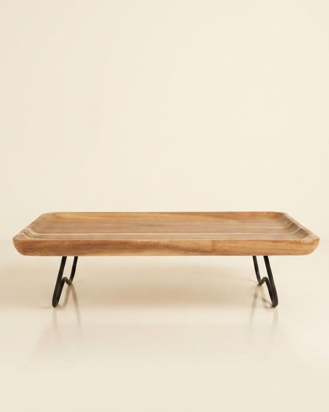 A rectangular wooden serving tray with a natural wood grain top and black metal hairpin legs, Elevated Wood Serving Tray, Raised Wooden Platter with Metal Legs, Wood and Metal Serving Board, Nature Enthusiast Home Decor, Rectangular Wood Table Riser, Solid Hardwood Buffet Platter, Rustic Modern Raised Serving Tray, Black Metal Base Wood Tray, Charcuterie Platter Riser, Biophilic Kitchen Serving Accessories