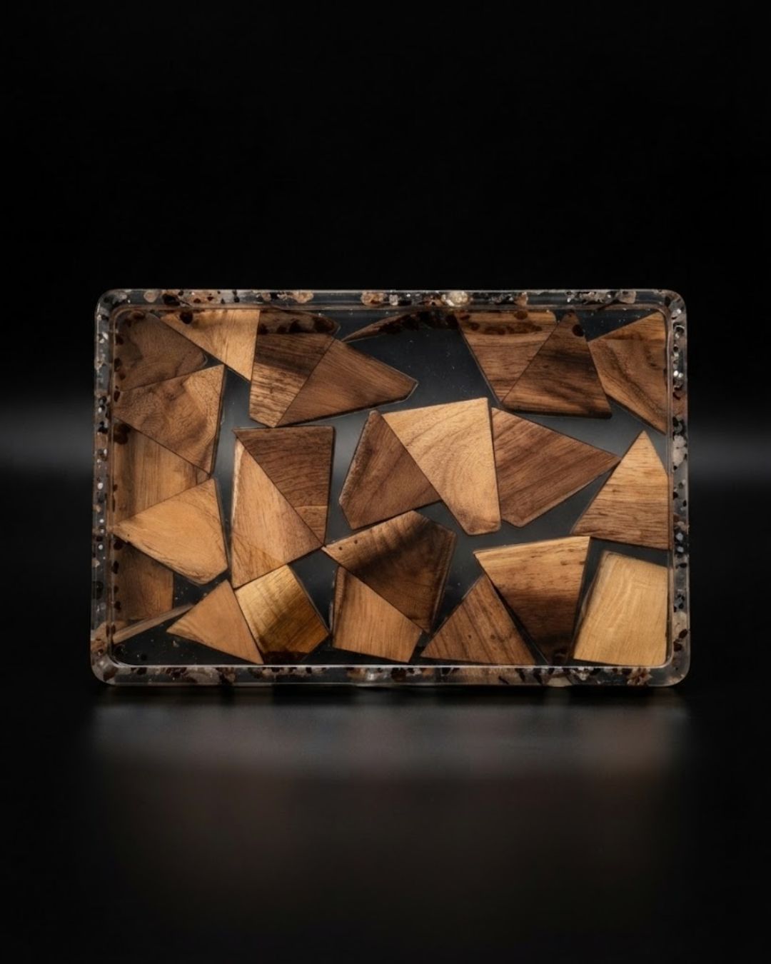 A rectangular tray with a mosaic pattern of irregular wooden triangles in various shades of brown, set in a clear resin frame, Wood and Epoxy Resin Serving Tray, Rectangular Resin Serving Platter, Geometric Wood Mosaic Tray, Nature Enthusiast Home Decor, Clear Epoxy Charcuterie Board, Natural Timber Accent Tray, Organic Wood Coffee Table Tray, Artisan Resin Drink Tray, Rectangular Wood Serving Board, Biophilic Home Accessories