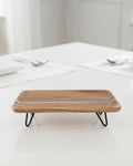 A rectangular wooden serving tray with a natural wood grain top and black metal hairpin legs, Elevated Wood Serving Tray, Raised Wooden Platter with Metal Legs, Wood and Metal Serving Board, Nature Enthusiast Home Decor, Rectangular Wood Table Riser, Solid Hardwood Buffet Platter, Rustic Modern Raised Serving Tray, Black Metal Base Wood Tray, Charcuterie Platter Riser, Biophilic Kitchen Serving Accessories
