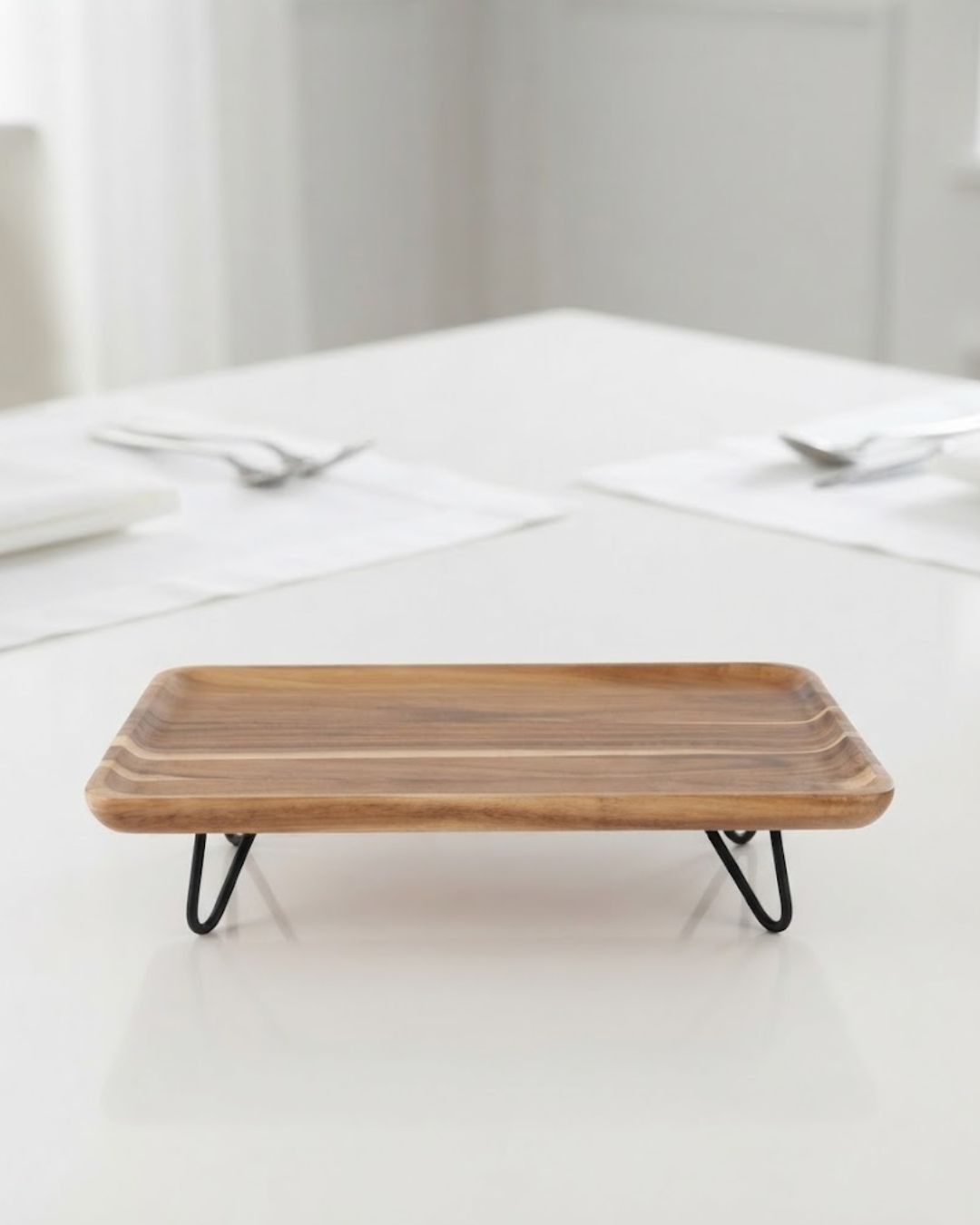 A rectangular wooden serving tray with a natural wood grain top and black metal hairpin legs, Elevated Wood Serving Tray, Raised Wooden Platter with Metal Legs, Wood and Metal Serving Board, Nature Enthusiast Home Decor, Rectangular Wood Table Riser, Solid Hardwood Buffet Platter, Rustic Modern Raised Serving Tray, Black Metal Base Wood Tray, Charcuterie Platter Riser, Biophilic Kitchen Serving Accessories
