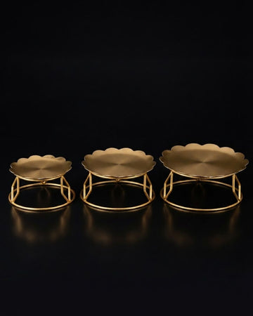 Three gold metal pedestal stands of different heights, Golden Metal Buffet Risers, Round Food Presentation Risers, Floral Scalloped Cake Pedestal, Nature Enthusiast Party Decor, Gold Tiered Dessert Stand, Separable Plate Buffet Display, Botanical Golden Serving Risers, Metal Tabletop Riser Set, Nesting Food Display Pedestals, Elevated Charcuterie Stand Gold