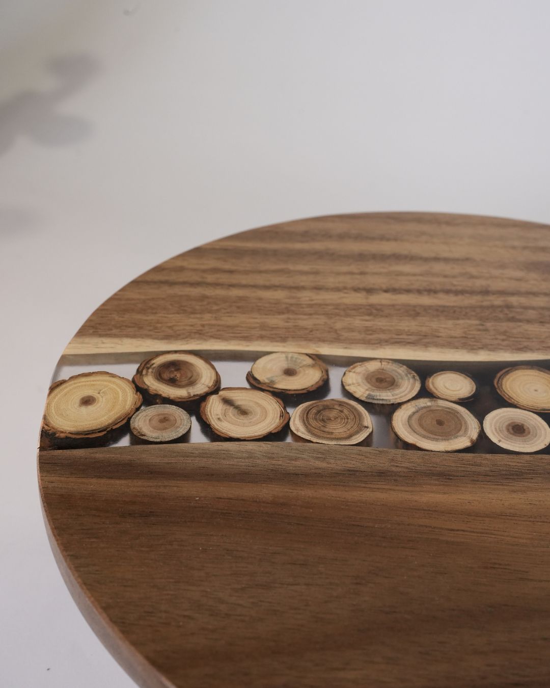 A close-up of a round wooden tray or tabletop featuring a decorative channel filled with cut wood slices, Wood and Epoxy Resin Cake Stand, Round Wooden Cheese Pedestal, Tree Slice Resin Dessert Riser, Nature Enthusiast Bakery Decor, Handmade Wood Charcuterie Stand, Rustic Modern Cake Platter 12 Inch, Resin River Cake Pedestal, Natural Wood Dessert Buffet Display, Elevated Cheese Board Wood Resin, Biophilic Home Kitchen Accessories