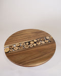 A round wooden serving board or tray with a natural wood grain finish and a central channel filled with small cut wood slices, Wood and Epoxy Resin Cake Stand, Round Wooden Cheese Pedestal, Tree Slice Resin Dessert Riser, Nature Enthusiast Bakery Decor, Handmade Wood Charcuterie Stand, Rustic Modern Cake Platter 12 Inch, Resin River Cake Pedestal, Natural Wood Dessert Buffet Display, Elevated Cheese Board Wood Resin, Biophilic Home Kitchen Accessories