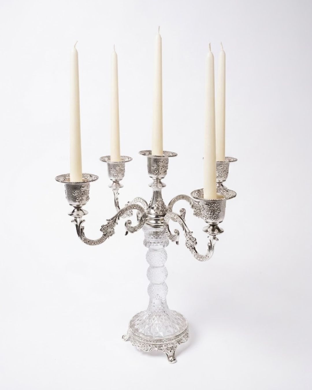 An ornate five-arm silver candelabra with a clear cut-glass pedestal base, holding five cream-colored taper candles, photographed against a plain white background.
Silver 5 Candle Stand, 5 Arm Candelabra Centerpiece, Glass and Metal Candle Holder, Wedding Table Candelabra Wholesale, VIP Dinner Party Candle Stand, High End Catering Table Centerpiece, Taper Candle Candelabra Silver, Vintage Silver Table Candle Holder, 11 Inch Candelabra Centerpiece, Luxury Event Decor Candle Stand