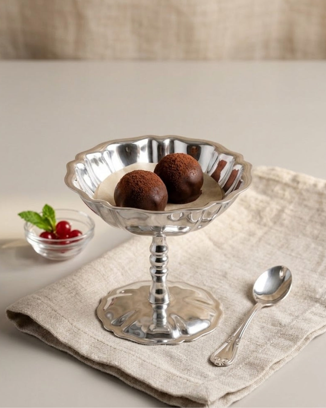 A silver pedestal dessert bowl with a scalloped rim, holding two chocolate-covered spheres, styled on a beige linen napkin with a spoon and a small bowl of red berries.

Silver Stainless Steel Dessert Bowl, Pedestal Ice Cream Cup, Silver Sundae Dish, Metal Sorbet Goblet, Individual Catering Dessert Cup, Fluted Silver Fruit Bowl, Vintage Style Stainless Steel Dessert Cup, Shatterproof Catering Dessert Ware USA, Commercial Ice Cream Pedestal Dish, Polished Silver Mousse Bowl