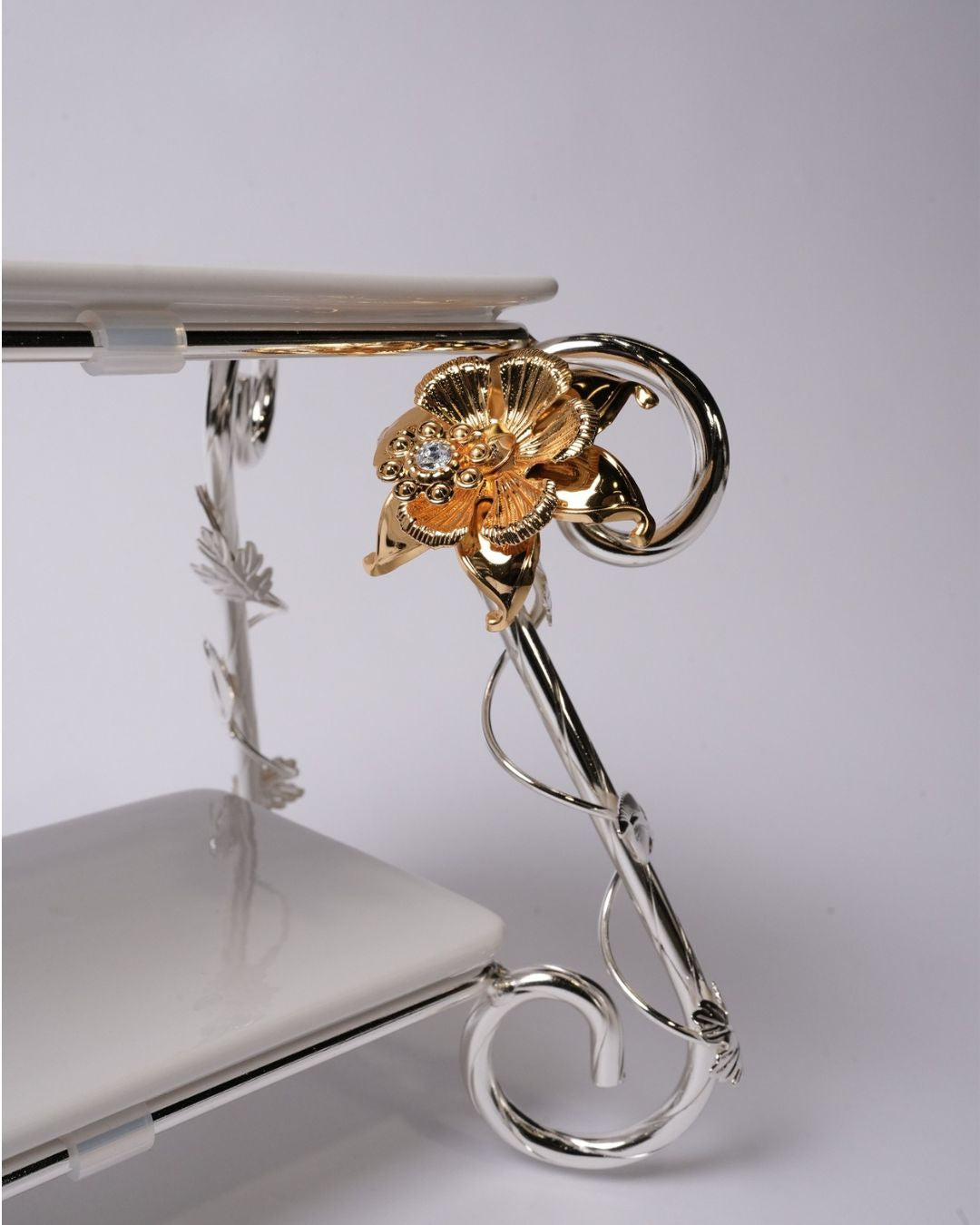 A close-up of an ornate two-tier display stand with a polished silver metal frame featuring a decorative gold flower accent with a clear rhinestone, holding white rectangular plates.

Silver 2 Tier Serving Stand, Two Tier Ceramic Dessert Stand, High End Catering Dessert Tray, Botanical Bird Food Stand, Rectangular Ceramic Serving Rack, Luxury Party Dessert Display, Silver Metal Tiered Pastry Stand, Upscale Wedding Dessert Tower, Two Tone Buffet Serving Rack, Double Layer Macaron Stand, Gold and Silver Tiere