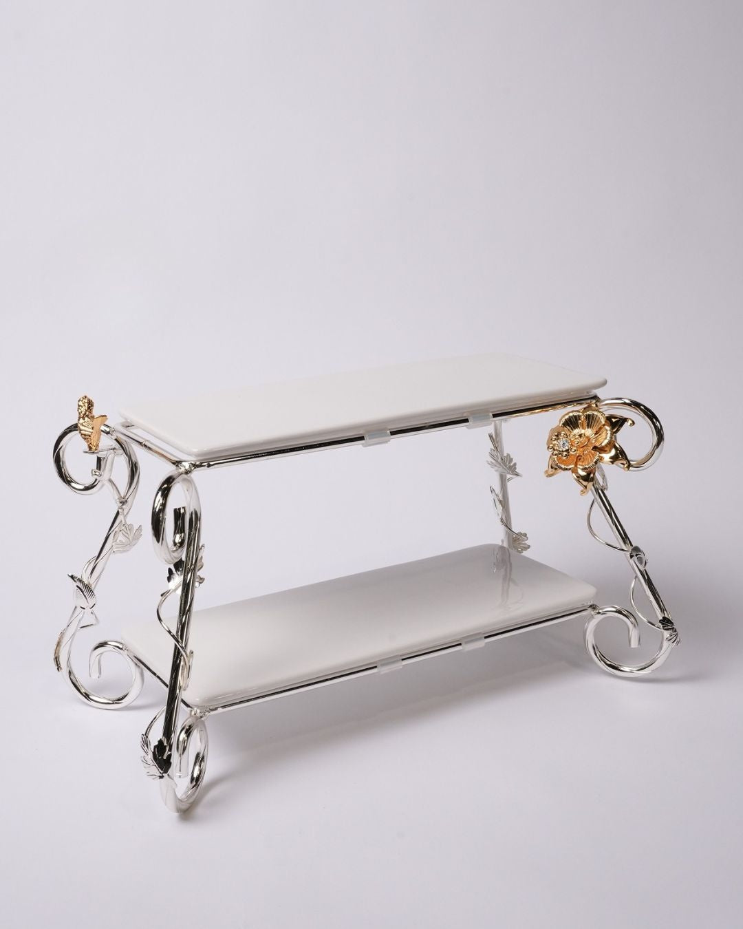 A two-tiered decorative display stand with a polished silver metal frame and white rectangular shelves, accented by gold-toned floral details on the corner supports, set against a plain light gray background.

Silver 2 Tier Serving Stand, Two Tier Ceramic Dessert Stand, High End Catering Dessert Tray, Botanical Bird Food Stand, Rectangular Ceramic Serving Rack, Luxury Party Dessert Display, Silver Metal Tiered Pastry Stand, Upscale Wedding Dessert Tower, Two Tone Buffet Serving Rack, Double Layer Macaron St