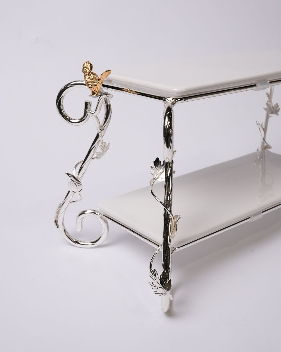 A two-tiered white ceramic shelf with an ornate silver metal frame featuring vine and leaf details, a small gold bird accent on the top corner, and a white background.

Silver 2 Tier Serving Stand, Two Tier Ceramic Dessert Stand, High End Catering Dessert Tray, Botanical Bird Food Stand, Rectangular Ceramic Serving Rack, Luxury Party Dessert Display, Silver Metal Tiered Pastry Stand, Upscale Wedding Dessert Tower, Two Tone Buffet Serving Rack, Double Layer Macaron Stand, Gold and Silver Tiered Tray